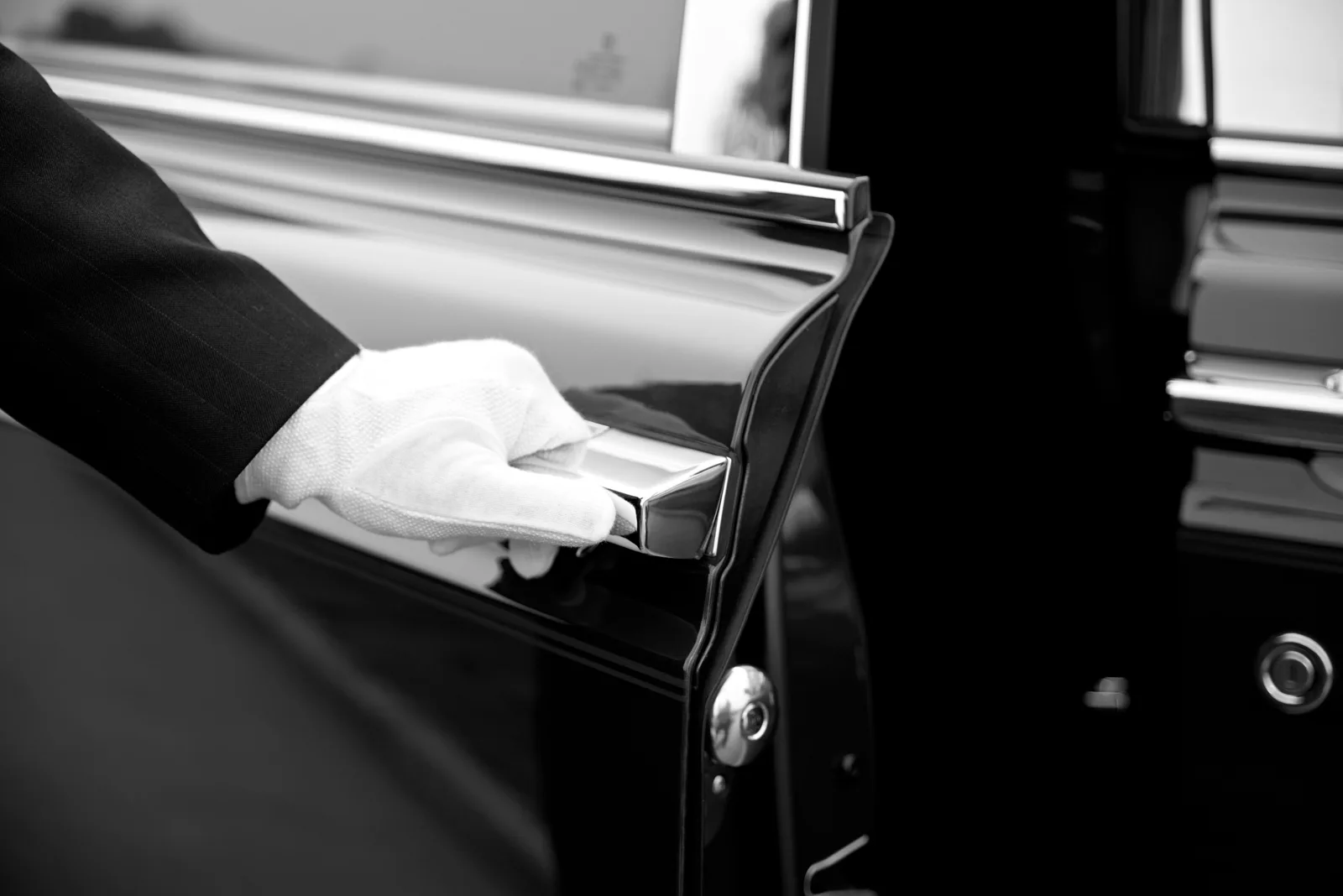 Imperial chauffeur in white gloves opening a luxury vehicle door
